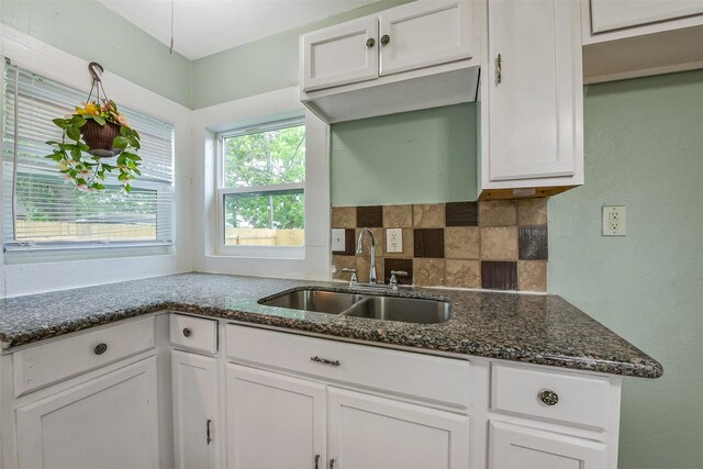 kitchen featuring dark stone counters, white cabinetry, a sink, and tasteful backsplash