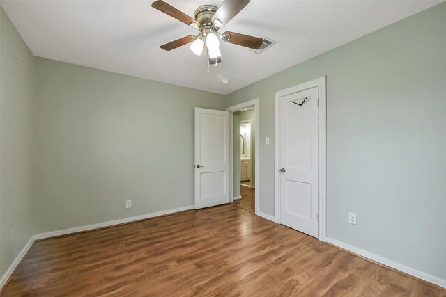unfurnished bedroom with a ceiling fan, baseboards, visible vents, and wood finished floors