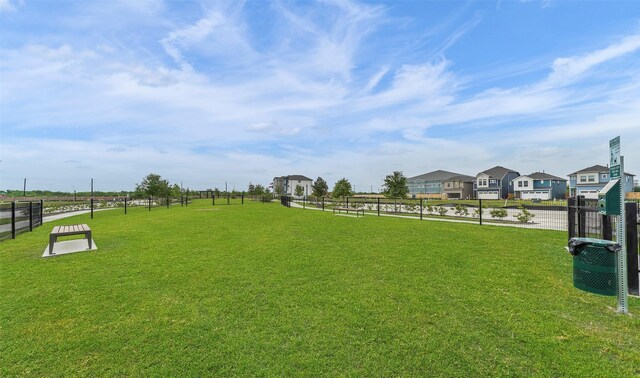 view of home's community with fence, a yard, and a residential view