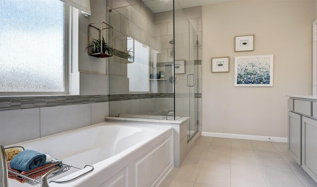 bathroom featuring a garden tub, tile patterned flooring, vanity, baseboards, and a stall shower