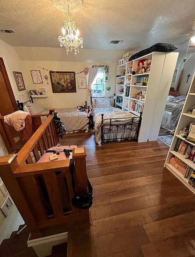 bedroom featuring a chandelier, hardwood / wood-style flooring, a textured ceiling, and visible vents