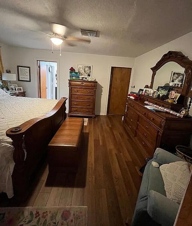 bedroom with a ceiling fan, dark wood-type flooring, a textured ceiling, and visible vents