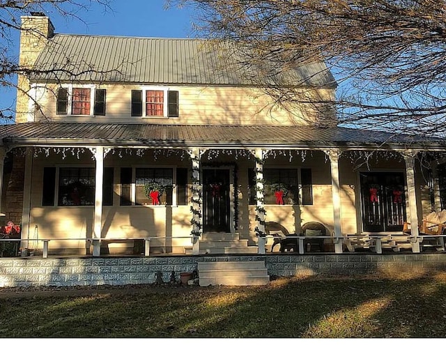 view of front of property featuring covered porch, a chimney, and metal roof