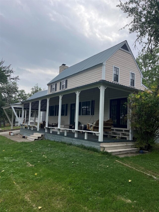 back of property featuring covered porch, a yard, and a chimney
