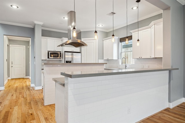1033 Herkimer St, Houston, TX 77008 - kitchen featuring decorative backsplash, ornamental molding, white cabinets, island exhaust hood, and appliances with stainless steel finishes