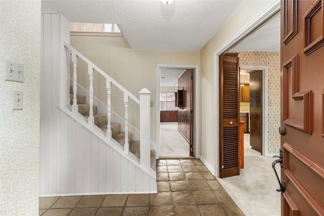 605 N Rivershire Dr, Conroe, TX 77304 - carpeted entryway featuring stairway, baseboards, wallpapered walls, and a textured ceiling