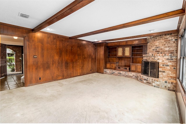 605 N Rivershire Dr, Conroe, TX 77304 - unfurnished living room with carpet floors, visible vents, a fireplace, beamed ceiling, and wooden walls