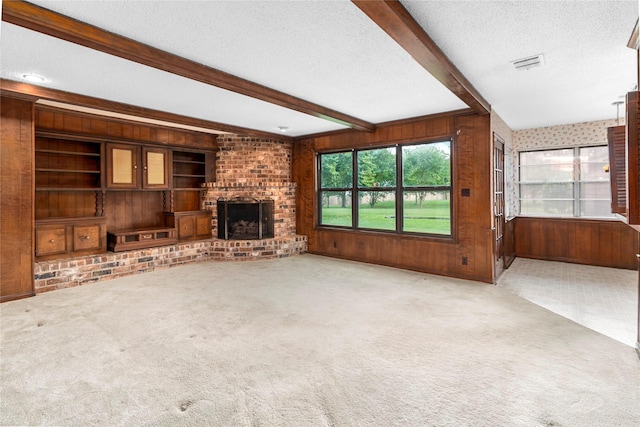 605 N Rivershire Dr, Conroe, TX 77304 - unfurnished living room featuring plenty of natural light, a textured ceiling, visible vents, beamed ceiling, and wooden walls