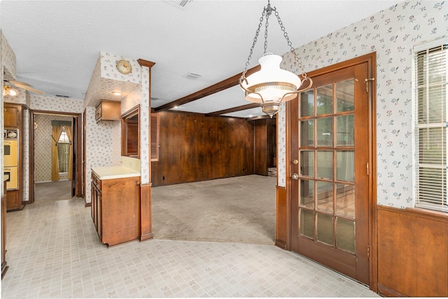 605 N Rivershire Dr, Conroe, TX 77304 - interior space with a textured ceiling, wood walls, beamed ceiling, ceiling fan with notable chandelier, and wallpapered walls