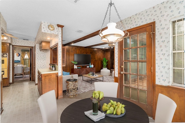 605 N Rivershire Dr, Conroe, TX 77304 - dining space with visible vents, beamed ceiling, wooden walls, wallpapered walls, and a textured ceiling