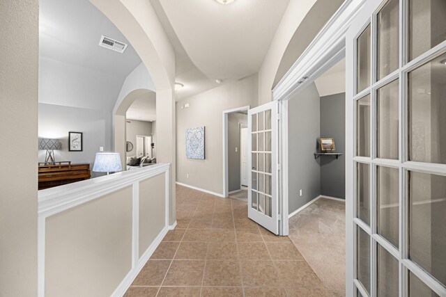 corridor featuring arched walkways, tile patterned floors, french doors, baseboards, and visible vents