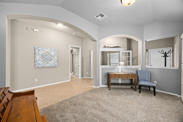living area featuring arched walkways, tile patterned floors, baseboards, lofted ceiling, and visible vents