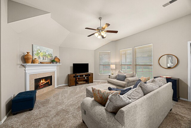 carpeted living room featuring ceiling fan, baseboards, vaulted ceiling, a tile fireplace, and visible vents