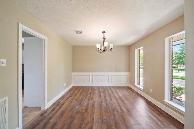 unfurnished dining area with hardwood / wood-style floors, a chandelier, and a textured ceiling