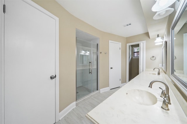 full bathroom featuring a stall shower, wood finished floors, double vanity, and baseboards