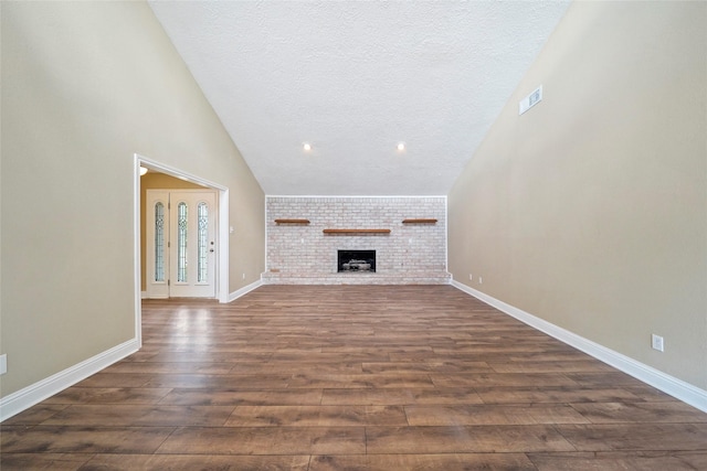 unfurnished living room featuring dark wood-type flooring, a textured ceiling, baseboards, a brick fireplace, and high vaulted ceiling