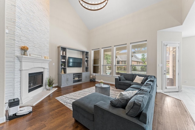 living room featuring baseboards, a healthy amount of sunlight, high vaulted ceiling, and a large fireplace