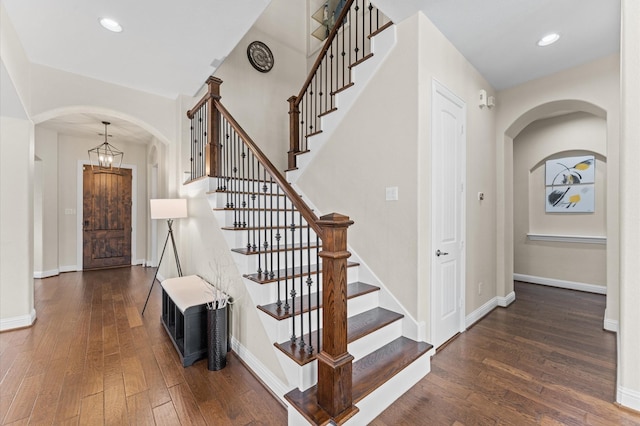 interior space with arched walkways, baseboards, and hardwood / wood-style floors