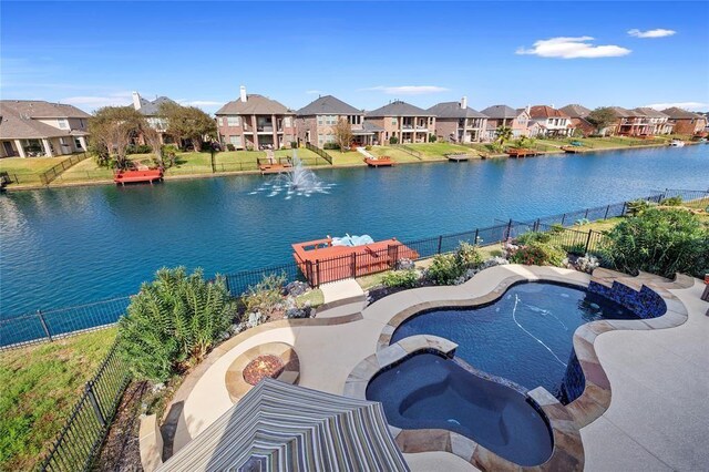 exterior space with a water view, a pool with connected hot tub, a residential view, and a fenced backyard