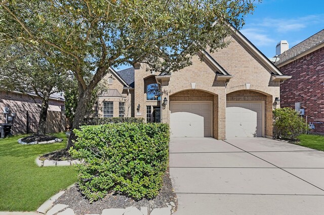 view of front of property featuring concrete driveway, brick siding, a garage, and a front lawn