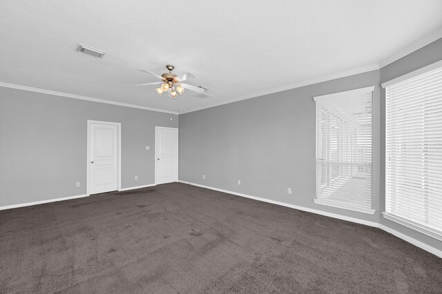 unfurnished room featuring visible vents, crown molding, baseboards, dark colored carpet, and ceiling fan