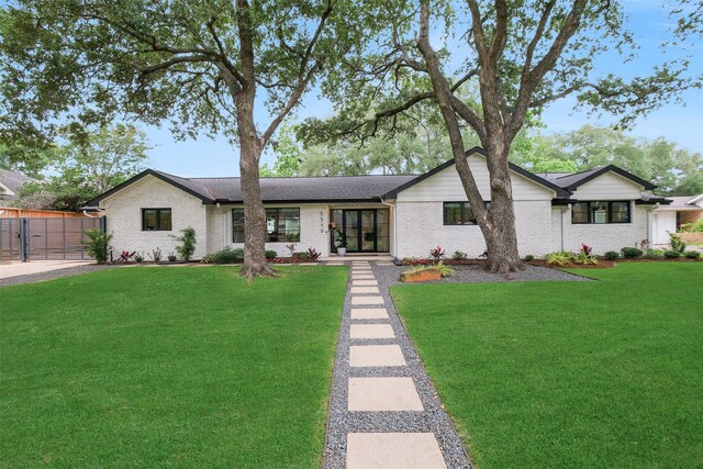 ranch-style house featuring a gate, brick siding, and a front yard