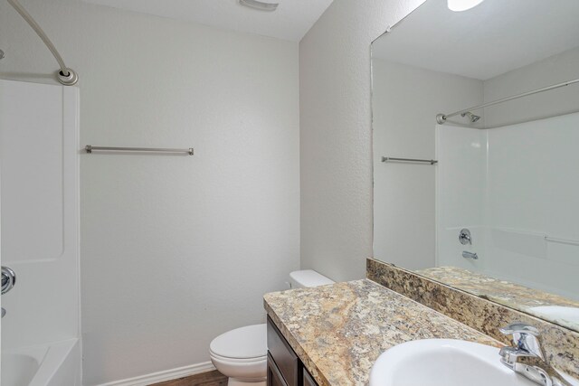bathroom featuring toilet,  shower combination, baseboards, and vanity