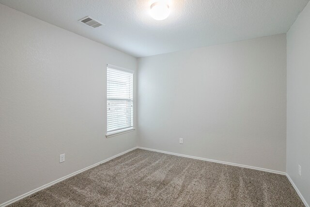 empty room with carpet floors, baseboards, and visible vents