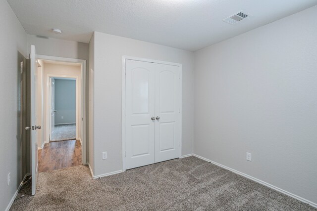 unfurnished bedroom with carpet floors, baseboards, a closet, and visible vents