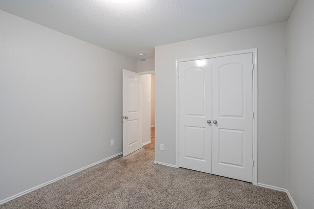 unfurnished bedroom with a closet, carpet flooring, and baseboards