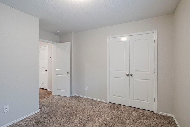 unfurnished bedroom with baseboards, carpet, and a closet