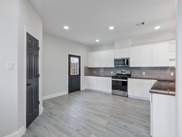 kitchen featuring visible vents, dark countertops, a sink, appliances with stainless steel finishes, and backsplash