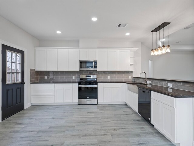 kitchen featuring open shelves, pendant lighting, a peninsula, a sink, and stainless steel appliances