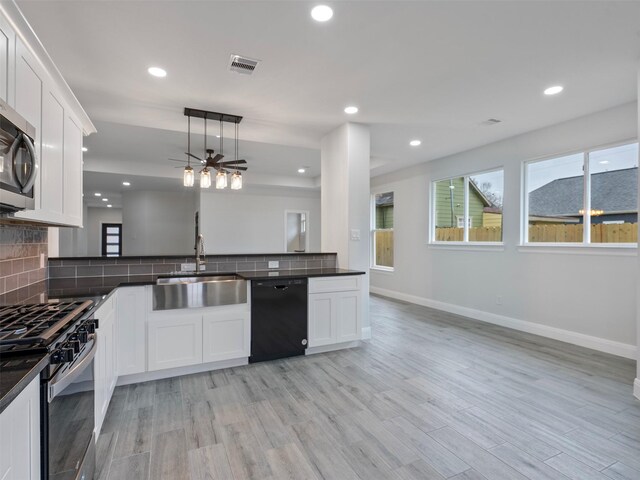 kitchen with dark countertops, a sink, black dishwasher, and gas range