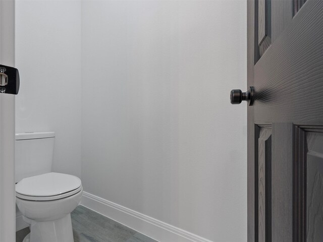 bathroom with baseboards, toilet, and wood finished floors