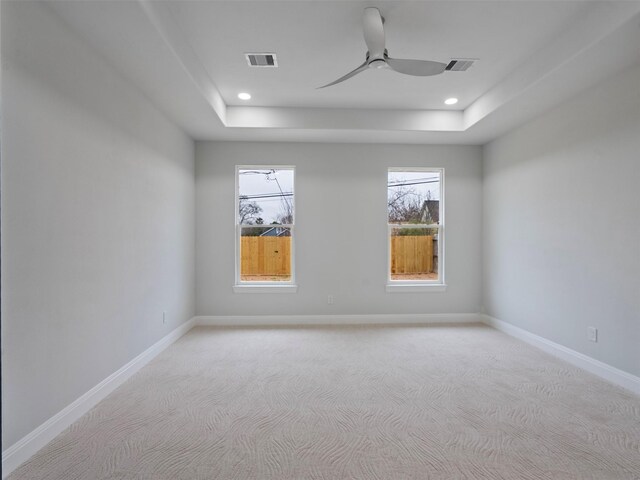 unfurnished room with visible vents, light carpet, a wealth of natural light, and a raised ceiling