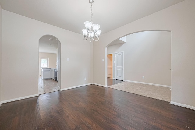 25451 Dappled Filly Dr, Tomball, TX 77375 - empty room with arched walkways, baseboards, a notable chandelier, and wood finished floors