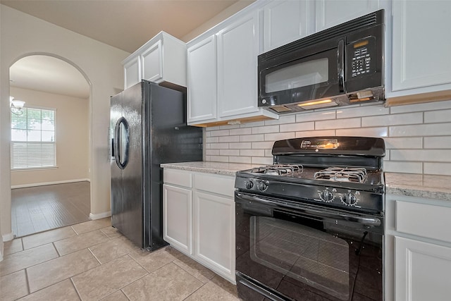 25451 Dappled Filly Dr, Tomball, TX 77375 - kitchen featuring decorative backsplash, arched walkways, light stone counters, white cabinets, and black appliances