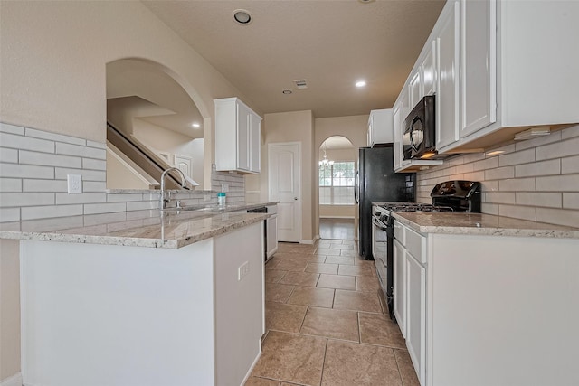 25451 Dappled Filly Dr, Tomball, TX 77375 - kitchen featuring arched walkways, white cabinets, black appliances, and tasteful backsplash