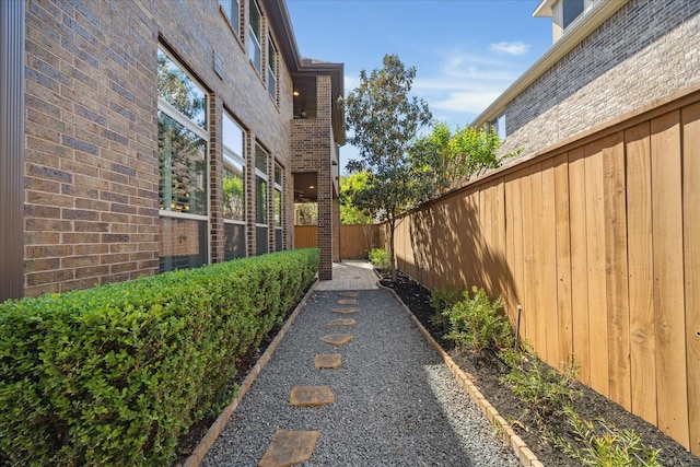 view of side of home with brick siding and fence