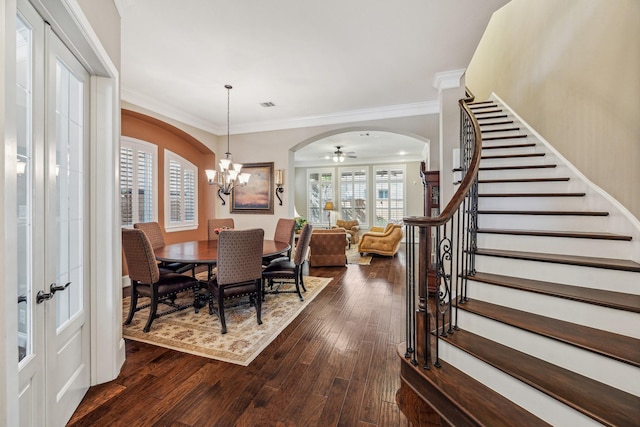 dining area with french doors, arched walkways, dark wood finished floors, ornamental molding, and stairs