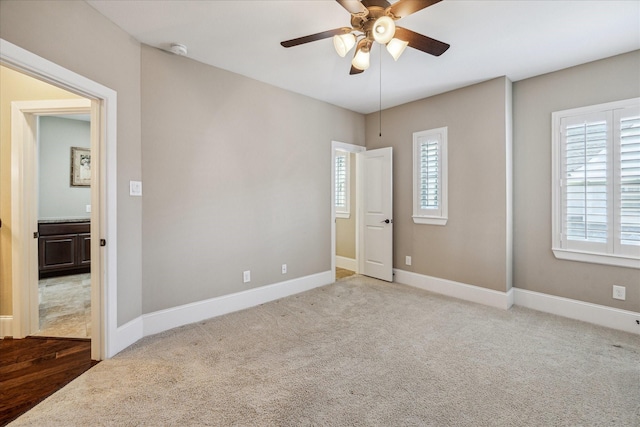 unfurnished bedroom with baseboards, a ceiling fan, carpet, and multiple windows