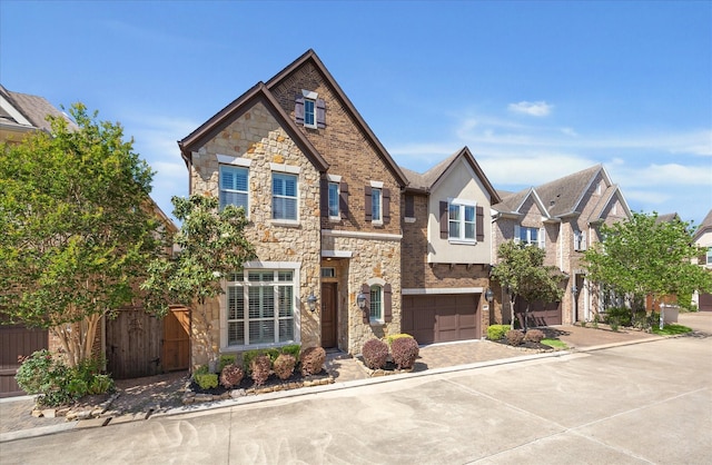 view of front facade with stucco siding, driveway, stone siding, and a garage