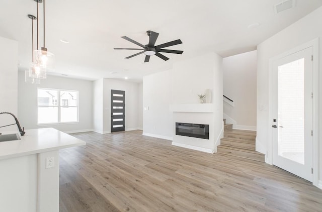 66 Westwood Dr E, Trinity, TX 75862 - unfurnished living room featuring visible vents, a sink, baseboards, light wood finished floors, and stairs