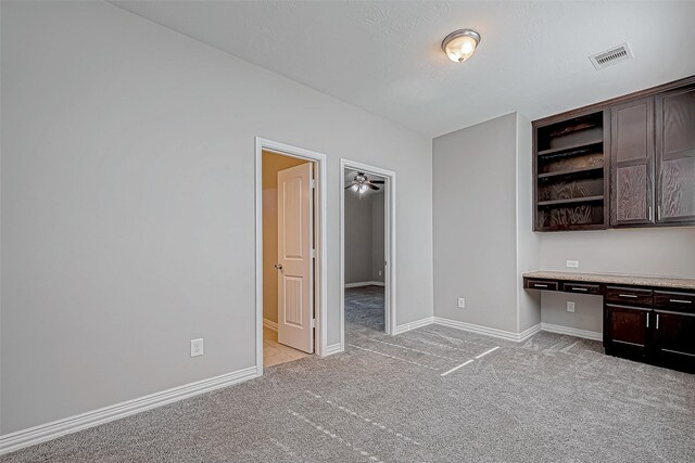 interior space featuring dark brown cabinets, open shelves, light colored carpet, light countertops, and visible vents