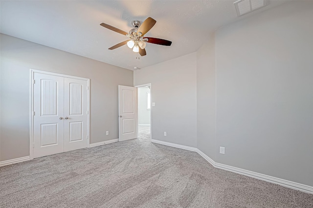 unfurnished bedroom with a ceiling fan, visible vents, baseboards, a closet, and carpet