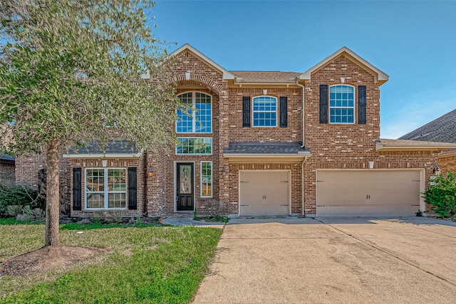 view of front of house with roof with shingles, an attached garage, a front lawn, brick siding, and concrete driveway
