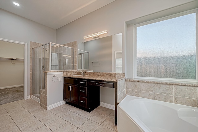 full bath with a garden tub, vanity, a walk in closet, tile patterned floors, and a shower stall