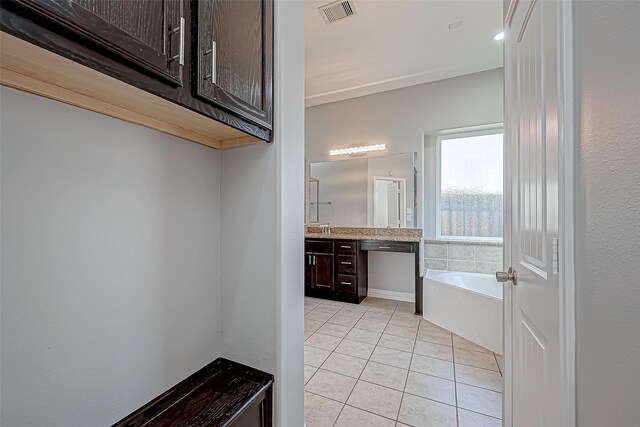 bathroom with tile patterned floors, visible vents, a bath, and vanity