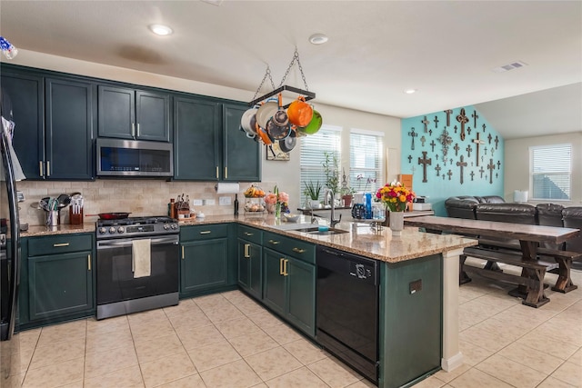 9530 Tipton Sands Dr, Humble, TX 77396 - kitchen with a sink, a peninsula, visible vents, light stone countertops, and appliances with stainless steel finishes